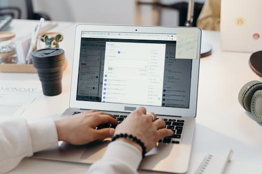 A person typing on a laptop in a bright, modern office setting, showing productivity and technology.